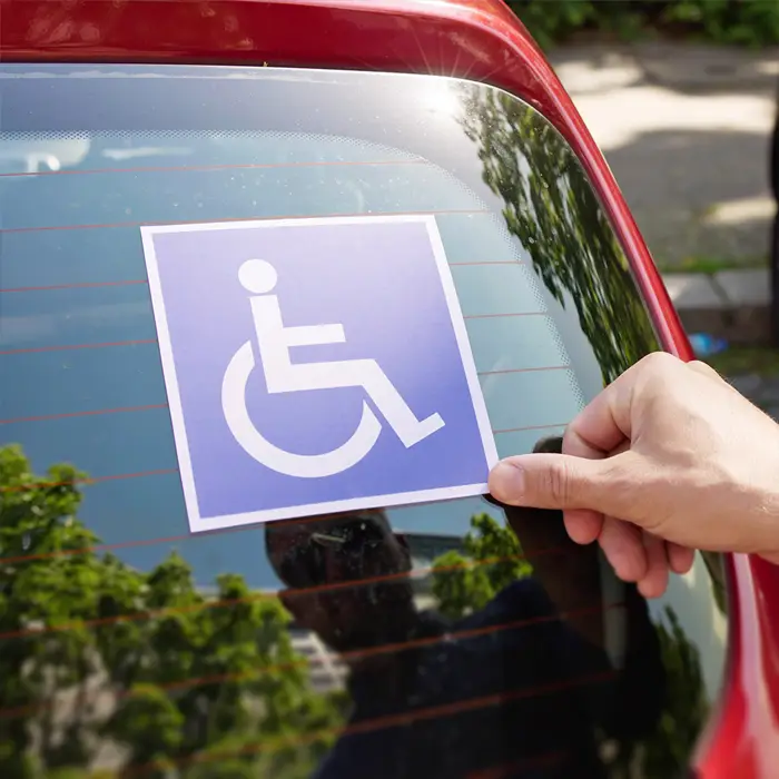 Auf den Heckscheiben mancher Autos sieht man einen blauen Aufkleber mit weißem Piktogramm eines Rollstuhlfahrers. Dieser Aufkleber soll auf die Behinderung des Fahrers aufmerksam machen.